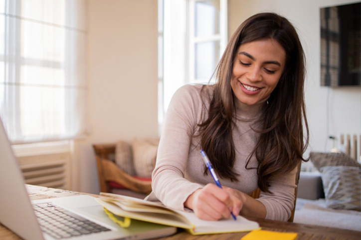 Woman working from home with a boston terrier dog. Freelancer businesswoman using laptop at sunny room. Student learning and working at home.