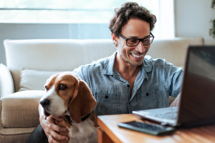 Mid-aged man comfortably working at home sitting on the floor with his Beagle dog by his side Mid-aged man comfortably working at home sitting on the floor with his Beagle dog by his side
