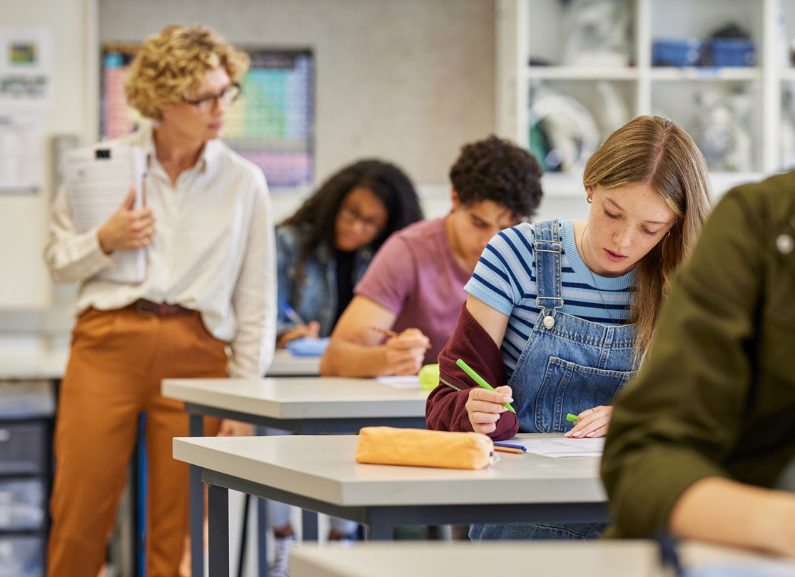 Female teacher observes students during exam at high school