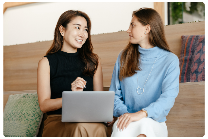 Refer a Friend Refer a friend - Two women having a conversation while working together on a laptop.